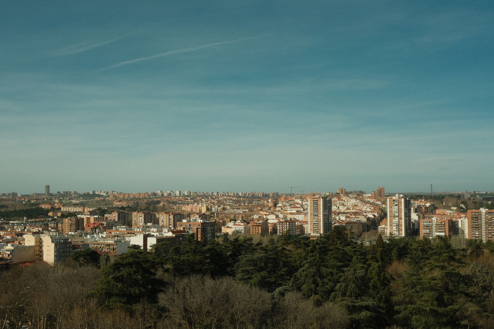 A wide view of Madrid's skyline under a clear blue sky, surrounded by urban architecture and greenery.